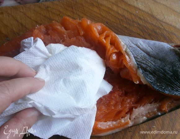 С помощью бумажного полотенца удалить кость. Удалить оставшиеся рёберные кости. Промыть и высушить рыбу изнутри.Слегка натереть солью.