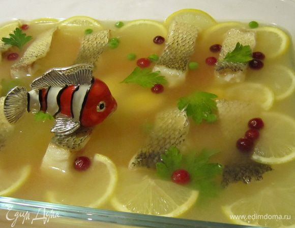 Когда рыбный бульон немного застынет, выложите на него кусочки рыбы (оставляя промежутки между кусочками), половинки перепелиных яиц, цветочки из моркови, дольки лимона, листики петрушки, клюкву и зеленый горошек. Залейте бульоном так, чтобы его слой над куском рыбы был 0,5–0,8 см и снова поставьте в холодное место для застывания.