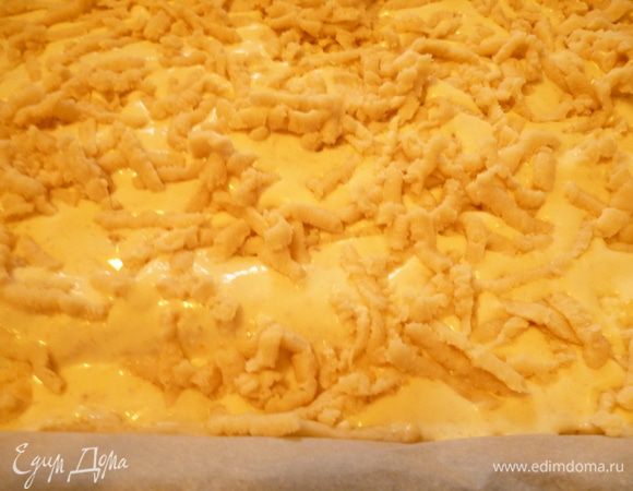 Достаем тесто из морозильника и с помощью терки распределяем его по поверхности  пирога.Этот слой теста будет совсем не большим,но он предохранит творожный слой от пригорания и по румяному цвету этого тертого слоя теста легче будет определить готовность пирога.