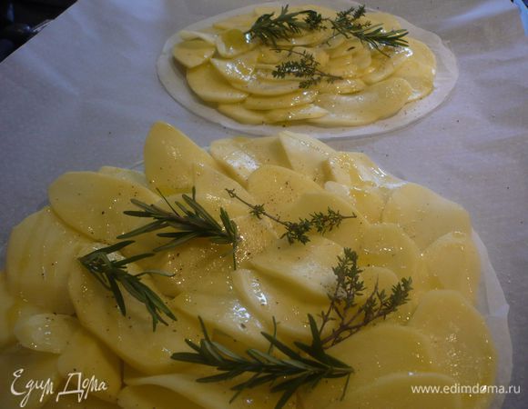 На противне, выложенном пекарской бумагой, разместить два круга из бумаги, а на них аккуратно расположить тонко порезанный сырой картофель, посолить, поперчить, выложить веточки тимьяна и розмарина. Ставим в духовку вместе с выложенной на другой противень морковью. Выпекаем 30- 40 минут.