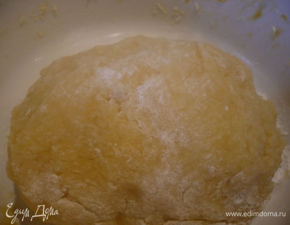 Делаем картофельное тесто для двух «коржей». Картофель в мундире чистим (лучше, конечно, почистить его, когда он еще теплый, так проще), натираем на мелкой терке, добавляем яйца, перемешиваем, вводим муку, соль и перец и снова хорошо перемешиваем. Раскатываем на доске, покрытой пергаментом, до размера формы и при помощи пергамента перекладываем в форму. 