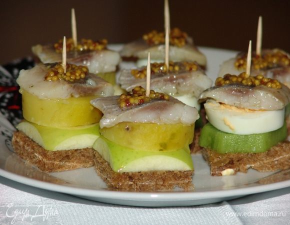 Чистим - нарезаем киви. Выкладываем на кусочек черного хлеба киви, отварное вкрутую яйцо, селедку и сверху слегка смазываем горчицей. 