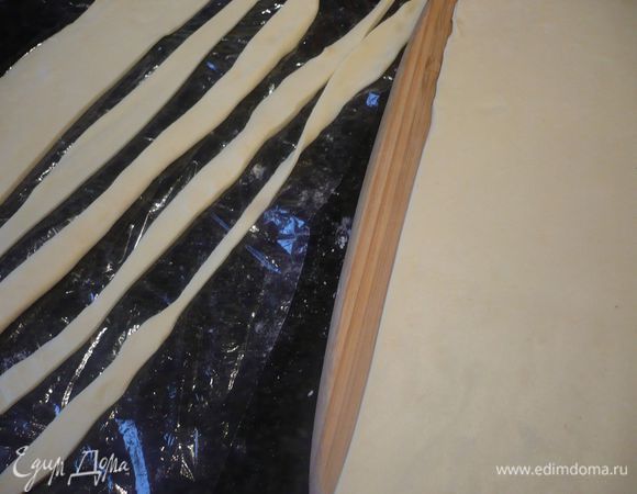 Духовку разогреваем до 200 градусов. Тесто достаем и укладываем его на посыпанную мукой поверхность, раскатываем тесто снова до прямоугольника периметром примерно 34 на 28 см. Теперь тесто готово к использованию. Обрезаем неровные края. 