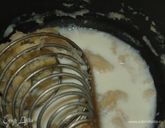 Вооружаемся венчиком, возвращаем сковородку на огонь средний и начинаем потихоньку вливать молоко, постоянно работая венчиком, сжимая и разжимая спиральку, разбивая комочки.
