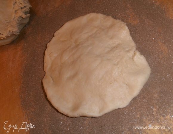 Отщипываем часть теста,разминаем в руках в пласт (если нужно - обмакиваем руки в муку) и кладём на присыпку.