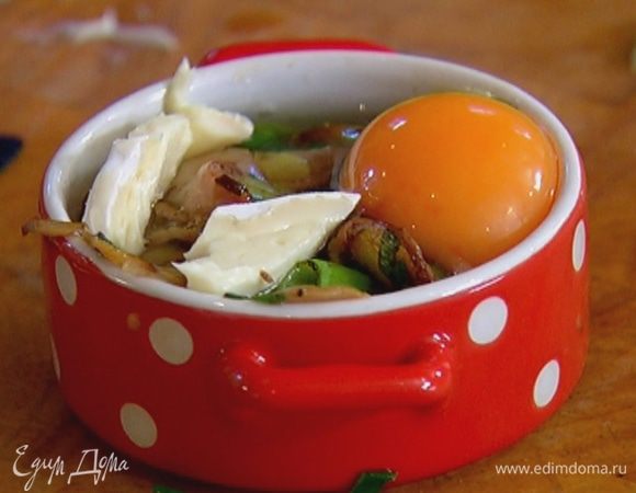 В две небольшие керамические формы выложить половину сыра, затем обжаренные грибы с беконом и луком, разбить по 1 яйцу так, чтобы желток не растекся, сверху разложить оставшийся сыр.