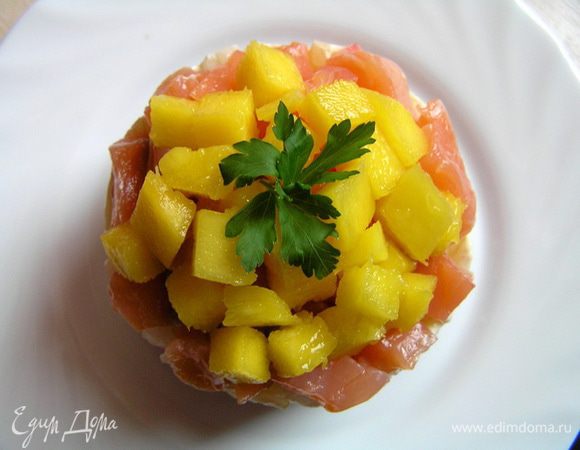 Перед подачей аккуратно снять кольца, сверху разложить нарезанный на маленькие кусочки манго, украсить петрушкой.