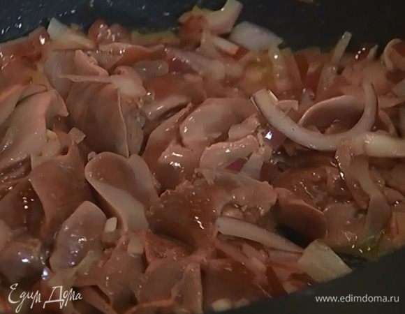 Разогреть в сковороде оставшееся оливковое масло, выложить лук, перемешать, добавить куриную печень, влить коньяк и обжаривать 5–7 минут.