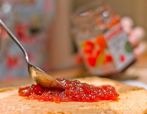 Выпекайте 12-15 минут в разогретой до 200 градусов духовке - пока поверхность не станет упругой при нажатии пальцем, а бисквит не начнет отходить от стенок формы. 
Посыпьте большой лист пергамента сахарной пудрой и выложите на него бисквит вверх дном. Дайте остыть в течение 5 минут и отклейте пергамент, в котором пекся бисквит. Намажьте джем на бисквит.