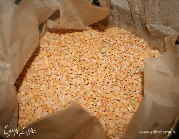 Часто проколем его вилкой, накроем пергаментом и сверху поместим груз - в моём случае это горох, также подойдёт сухая фасоль.