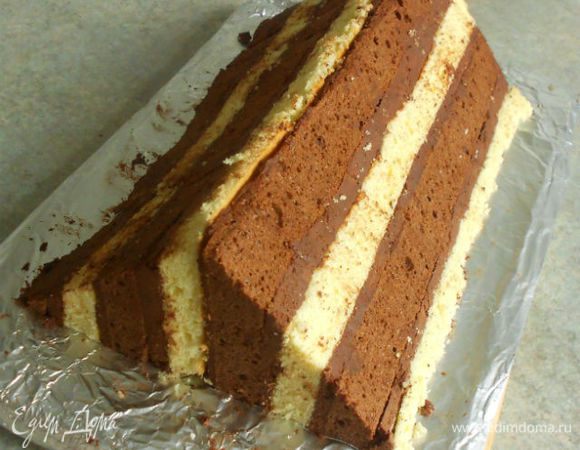 ...приложить к нему вторую половину светлым коржом, а разрезанной стороной кнаружи. Нежно прижать половинки друг к другу. Теперь пирог имеет форму большого треугольника.