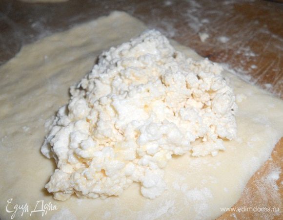 Тесто разделить на кусочки одинакового размера, каждый кусочек размять руками( лучше не раскатывать, а именно разминать руками). На каждый кусочек положить творожную начинку. Защипить края и сформировать в виде треугольничков.