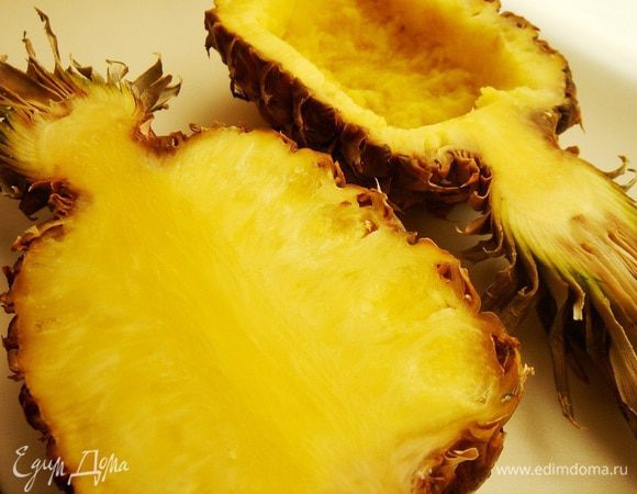 Ананасы вместе с хвостиками разрезать пополам. Отступив от края около 1 см надрезать ножом мякоть и аккуратно вынуть её ложкой или узкой лопаткой.