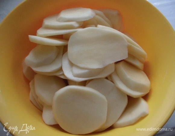 Картофель почистить, нарезать тонкими ломтиками(без фанатизма) или натереть на крупной терке. Очистить чеснок, разрезать пополам и натереть им дно и стенки жароустойчивой формы. Смазать ее сливочным маслом.