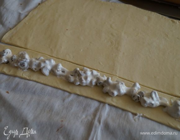Слоеное тесто раскатать и нарезать на широкие полосы, выложить начинку на середину полоски