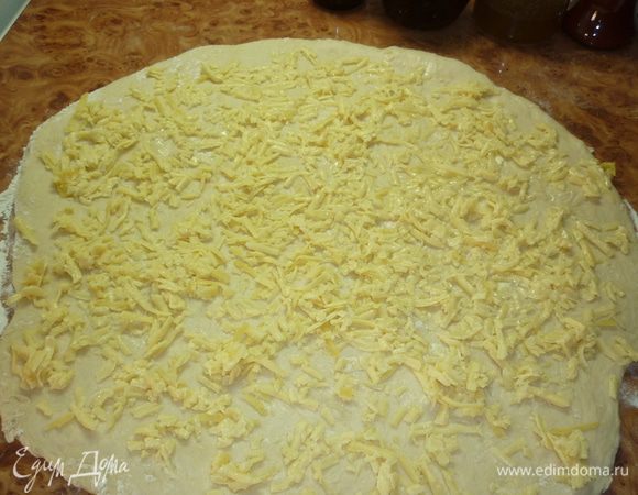 слышала, что дрожжевое тесто не раскатывают, оно становится жестким. возможно, я не настолько гурман, чтоб заметить разницу. я пробовала и раскатывать, и руками растягивать. результат всегда отличный. стол подпылить мукой. тесто раскатать, можно смазать растопленным сливочным маслом для большей нежности, сверху равномерно распределить сыр. люблю сыра побольше. а в этот раз получилось наоборот. ну так не беда. я планирую жить и после конца света, поэтому  у меня все впереди