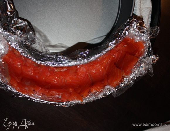 Выкладываем на дно тонкие ломтики семги, отложив примерно 150 г