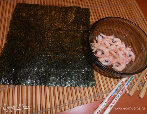 Продукты не успела сфотографировать, только вовремя шаги запечатлела... Вынимаем из пачки (у нас по 10 шт. продают) лист морских водорослей и кладём на бамбуковый коврик блестящей стороной вниз. Можно сбрызнуть рисовым уксусом.