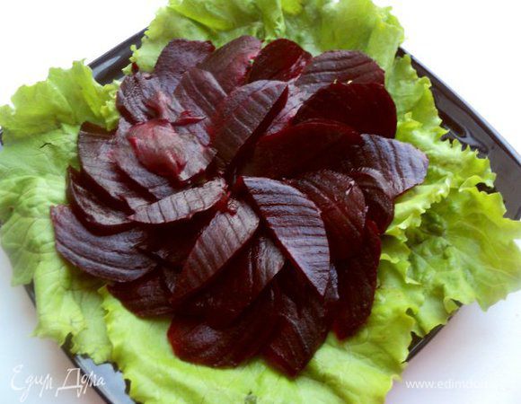 На блюдо уложить листья салата. У меня был обычный салат, но можно брать  и «Айсберг»  или другой салат по Вашему вкусу. Сверху выложить нарезанную тонкими ломтиками свеклу.