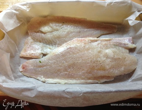 Противень застелить пергаментом. Выложить филе рыбы. Сверху положить смесь орехов, зелени и петрушки.