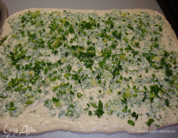 Духовку нагреть до 200 градусов. Чеснок пропустить через пресс и добавить к сливочному маслу и измельченной зелени. Тесто раскатать в тонкий пласт и нанести на него ровным слоем приготовленную начинку.