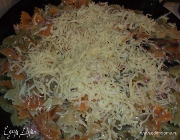 затем добавляем туда отварные макароны,посыпаем тёртым сыром,перемешиваем,выключаем газ