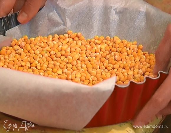 Охлажденное песочное тесто накрыть бумагой для выпечки, насыпать сверху горох или любую крупу и отправить в разогретую духовку на 10–15 минут.