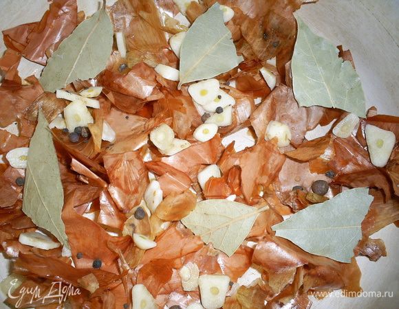 Луковую шелуху промываем и распределяем по дну кастрюльки, в которой будут готовиться наши "шпроты". Ее следует взять такую, чтоб можно было поставить в духовку.  Старайтесь укрыть шелухой все дно, чтоб рыбка не прилипла. Сверху выкладываем лавровый лист, перец горошком и почищенный и нарезанный пластинками чеснок.