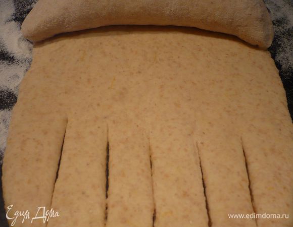 Вторую часть теста разделяем на шесть равных частей (Если Вы захотите украсить пирог дополнительно, например, розой, нужно отделить немного теста на этом этапе). Каждую часть раскатываем на присыпанной мукой поверхности в полоску шириной примерно в 12 см. Конец полоски разрезаем вдоль ножом 5 или 6 раз, как показано на фотографии. Скручиваем в «колбаску», начиная с неразрезанного конца, во время закручивания правый и левый конец закрываем. 