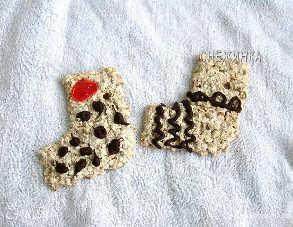 Немного остужаем растопленный шоколад, помещаем его в пакетик с отрезанным кончиком и рисуем на печенье узоры. Отправляем в холод, чтобы шоколад застыл.