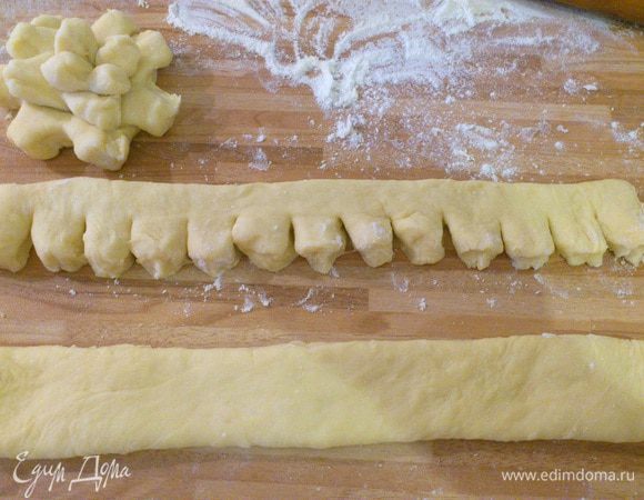 На посыпанной мукой поверхности быстро вымешиваем тесто руками, разделяем его на 2 части. Раскатываем скалкой в пласт приблизительно 25 на 20, разрезаем на 4 полоски, на каждой полоске делаем надрезы до середины, затем скатываем полоску так, как мы сворачиваем рулет, получается шишка.