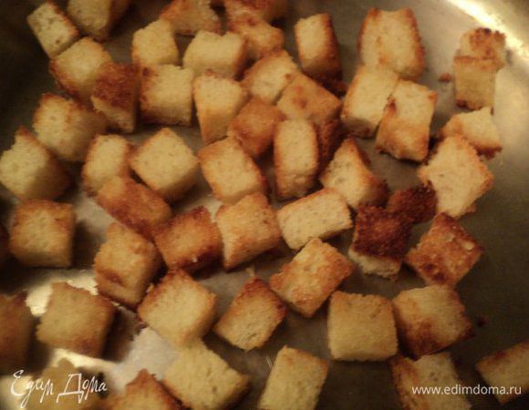 Батон обрезаем от корок и нарезаем кубиками 1х1 см. Выкладываем хлеб на противень и подсушиваем в духовке при температуре 180 градусов 5-7 мин. Мелко нарезаем чеснок и поджариваем его на оливковом масле до золотистого цвета, затем чеснок убираем и на этом ароматном масле поджариваем кубики батона до золотистого цвета.