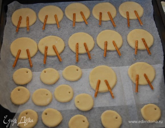 На присыпанной мукой поверхности раскатать тесто и вырезать 15 кружков d 7см. и столько же d 3,5см.  В бОльшие кружки слегка вдавить соломку, в маленьких при помощи коктельной  трубочки сделать дырочки для ленточек.   Выпекать около 20минут  при температуре 180гр.  Ориентируйтесь на свой духовой шкаф. 