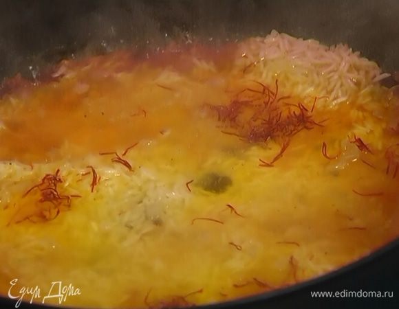 Через 5–10 минут влить замоченный шафран и оставшийся куриный бульон, снова накрыть крышкой и держать на небольшом огне до готовности риса.