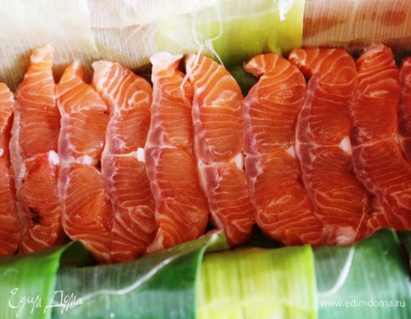 Выложить в прямоугольную высокую форму листья порея внахлест так, чтобы концы свисали с обеих сторон. На лук выложить слой семги. 