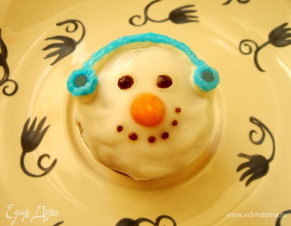 Лимонно-кокосовые кексы сразу покрыла растопленной помадкой. Смешать марципан с оранжевым красителем и слепить небольшие морковки и установить носики на кексы. Пока помадка подсыхала, плотные целлофановые пакеты или специальные конусообразные целлофановые мешки (у меня такие, свёрнутые в рулон, мешки) поместить понемногу белого и чёрного шоколада и опустить в горячую воду (я ставила ковшик с водой на маленький огонь и поддерживала воду горячей). Срезать небольшой уголок у пакета с чёрным шоколадом и выдавить на кекс 2 капельки- глазки и совсем маленькие- улыбающийся рот. Растопленный белый шоколад можно смешать с голубым или красным красителем и нарисовать снеговику тёплые ушки. 