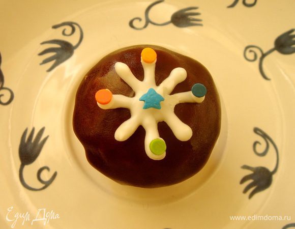 На пергаменте,расстеленном на доске, нарисовать простым карандашом снежинки ,перевернуть пергамент и обвести снежинки белым шоколадом. Если шоколад в пакетах застывает,то на секунды можно опустить пакет в горячую воду,зажав отверстие. Кончики снежинок украсить сахарными конфетти. Убрать пергамент со снежинками в холодильник на 10 минут,а затем выложить снежинки на кексы и слегка придавить по центру. Снежинок,ёлки и снеговиков дополнительно можно присыпать серебряным кондурином.  