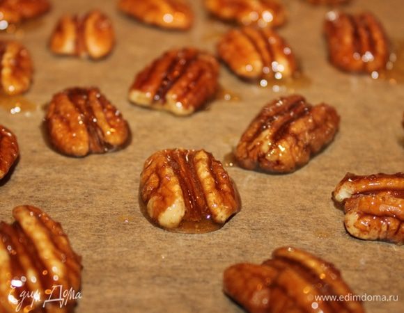 Пока коржи остывают, карамелизуем орехи для украшения. Растопить мед с сахаром, обмакнуть половинки орехов, выложить на лист пекарской бумаги и слегка запечь в нежаркой духовке.