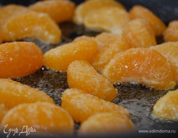 Разогреть в сковороде 20 г сливочного масла   обжарить дольки мандарин (по паре минут с каждой стороны), присыпав их чайной ложкой сахара.