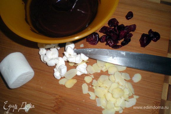 Растопить шоколад на водяной бане или в микроволновке. Маршмеллоу порубить, подготовить орехи и клюкву. Если клюква крупная, то тоже нарезать помельче.