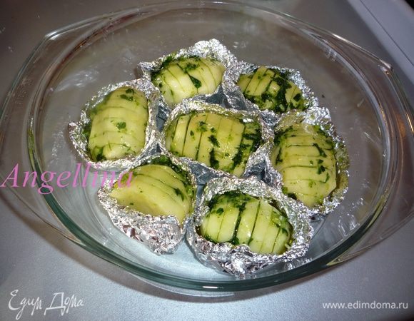 Картофель почистить, сделать надрезы не до конца, чтобы картофель не разрезать. Каждую надрезанную картофелину завернуть в фольгу, не защепляя фольгу сверху. Кисточкой покрыть картофелину чесночным соусом, аккуратно раздвигая надрезы на картофеле, чтобы соус с зеленью и чесноком попал и туда. Сложить «лодочки» с картофелем в форму и поставить в духовку запекаться примерно на час при температуре 190 градусов.