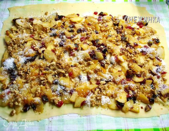 На тесто равномерно распределяем начинку, оставив верхний край немного свободным. Посыпаем кокосовой стружкой и орехами.