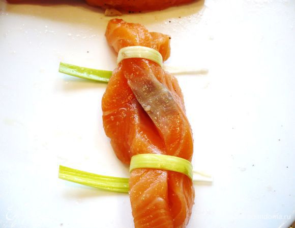 Духовку разогреваем до 180 градусов. Закрепляем сверху и снизу жгутик из семги полоской лука-порея. Можно попробовать другой вариант, разрезанные полоски семги положить плоско и надрезать вдоль так, чтобы можно было переплести между собой получившиеся полосочки. Затем проделать в кусочке рыбы сверху небольшое  отверстие и продеть через него полосочку лука-порея, затем обмотать ее вокруг жгутика. 