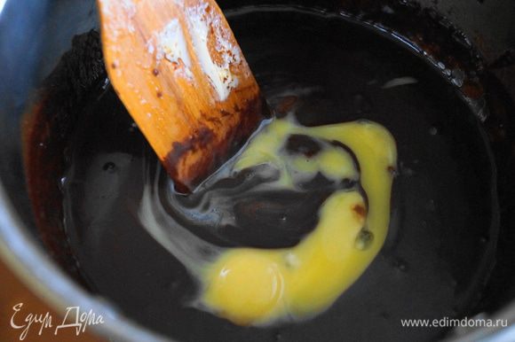 В шоколадно-масляную смесь добавить желтки и аккуратно перемешать