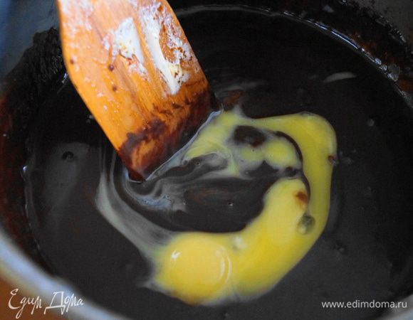 В шоколадно-масляную смесь добавить желтки и аккуратно перемешать