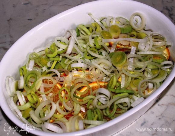 Сверху выложить лук-порей, порезанный колечками.
