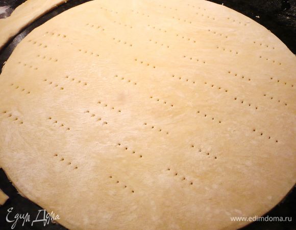 Достаем из холодильника вторую часть теста. Одну треть отделяем и раскатываем по диаметру формы, протыкаем по всему периметру вилкой. 