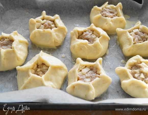 Выложить наши пирожки на противень, застеленный бумагой для выпечки и смазанный маслом, смазать их желтком, и поставить выпекать в разогретую до 180 градусов духовку на 15 минут
