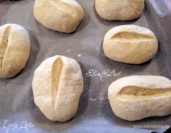 Теперь лезвием или острым ножом делаем надрез на булочках.
Прикрываем булочки полотенцем и даем постоять минут 30. А затем выпекаем в заранее разогретой до 200С духовке. Перед выпечкой сбрызнете духовку водой из пульверизатора.