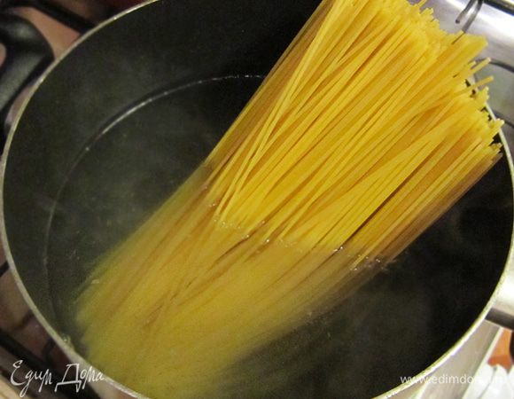 Спагетти отварить в большом количестве подсоленной воды до состояния al dente. Воду слить, но 1 чашку жидкости оставить.